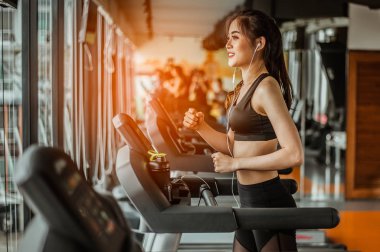 Spor salonunda koşu bandında koşan kadın portresi müzik dinliyor.Egzersiz konsepti. Fitness ve sağlıklı yaşam tarzı..