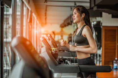 Spor salonunda koşu bandında koşan kadın portresi müzik dinliyor.Egzersiz konsepti. Fitness ve sağlıklı yaşam tarzı..