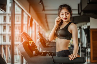 Spor salonunda koşu bandında koşan kadın portresi müzik dinliyor.Egzersiz konsepti. Fitness ve sağlıklı yaşam tarzı..