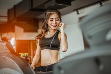 Spor salonunda koşu bandında koşan kadın portresi müzik dinliyor.Egzersiz konsepti. Fitness ve sağlıklı yaşam tarzı..