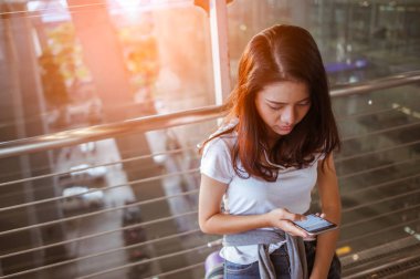 Kadınlar havaalanlarındaki uçuş kontrollerinde akıllı telefonlarını kullanıyorlar. Havaalanları ve teknoloji konsepti