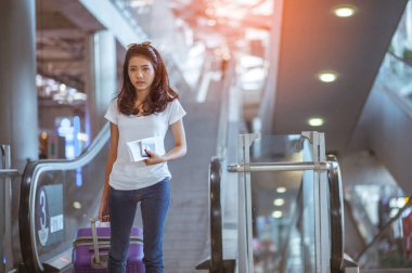 Modern havaalanı terminalinde bavulu çeken genç bir kadın. Taşıyıcıyı beklerken bavuluyla gezen adam. Dikiz aynası. Boşluğu kopyala