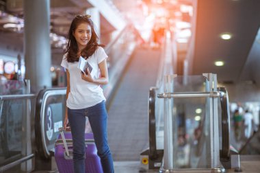 Modern havaalanı terminalinde bavulu çeken genç bir kadın. Taşıyıcıyı beklerken bavuluyla gezen adam. Dikiz aynası. Boşluğu kopyala