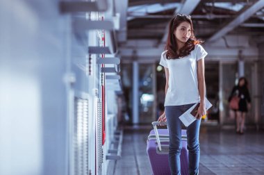 Modern havaalanı terminalinde bavulu çeken genç bir kadın. Taşıyıcıyı beklerken bavuluyla gezen adam. Dikiz aynası. Boşluğu kopyala