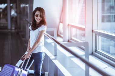 Modern havaalanı terminalinde bavulu çeken genç bir kadın. Taşıyıcıyı beklerken bavuluyla gezen adam. Dikiz aynası. Boşluğu kopyala