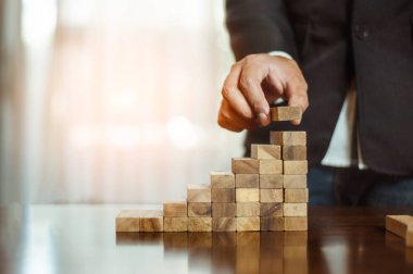 İş dünyasında plan ve strateji. Risk kavramı. İnsanın eli ahşap bir bloğu yığıp istifliyor..