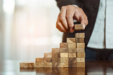 İş dünyasında plan ve strateji. Risk kavramı. İnsanın eli ahşap bir bloğu yığıp istifliyor..