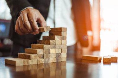 İş dünyasında plan ve strateji. Risk kavramı. İnsanın eli ahşap bir bloğu yığıp istifliyor..