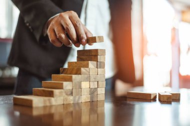 İş dünyasında plan ve strateji. Risk kavramı. İnsanın eli ahşap bir bloğu yığıp istifliyor..