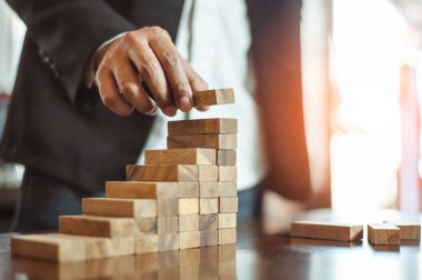 İş dünyasında plan ve strateji. Risk kavramı. İnsanın eli ahşap bir bloğu yığıp istifliyor..