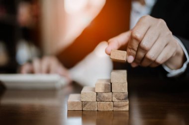 İş dünyasında plan ve strateji. Risk kavramı. İnsanın eli, tahtadan bir bloğu yığıp istifliyor. İşadamı, 