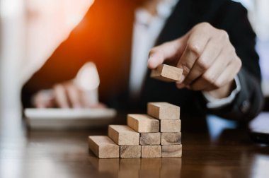 İş dünyasında plan ve strateji. Risk kavramı. İnsanın eli, tahtadan bir bloğu yığıp istifliyor. İşadamı, 