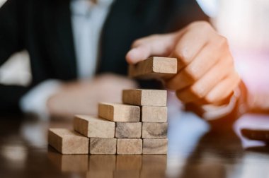 İş dünyasında plan ve strateji. Risk kavramı. İnsanın eli ahşap bir bloğu yığıp istifliyor..