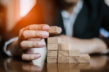 İş dünyasında plan ve strateji. Risk kavramı. İnsanın eli ahşap bir bloğu yığıp istifliyor..