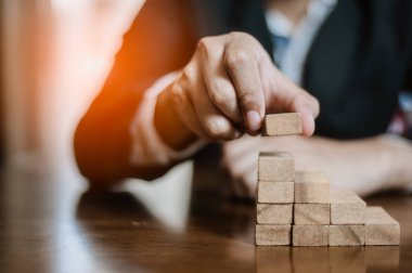 İş dünyasında plan ve strateji. Risk kavramı. İnsanın eli ahşap bir bloğu yığıp istifliyor..