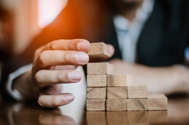 İş dünyasında plan ve strateji. Risk kavramı. İnsanın eli ahşap bir bloğu yığıp istifliyor..