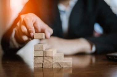 İş dünyasında plan ve strateji. Risk kavramı. İnsanın eli ahşap bir bloğu yığıp istifliyor..