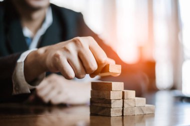 İş dünyasında plan ve strateji. Risk kavramı. İnsanın eli ahşap bir bloğu yığıp istifliyor..