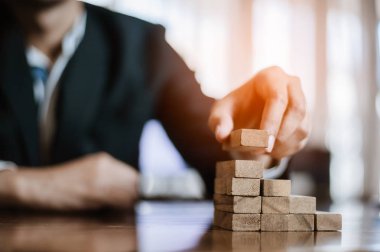 İş dünyasında plan ve strateji. Risk kavramı. İnsanın eli ahşap bir bloğu yığıp istifliyor..