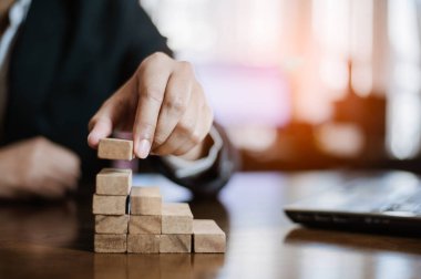 İş dünyasında plan ve strateji. Risk kavramı. İnsanın eli ahşap bir bloğu yığıp istifliyor..