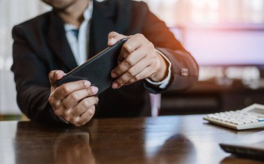 Molada akıllı telefonunda video oyunları oynayan bir işadamı.