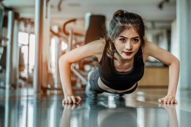 Spor salonunda şınav çeken genç bir kadın..