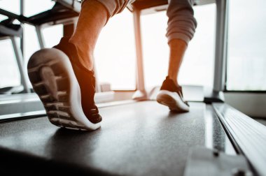 Ayakkabıya yaklaş, koşu bandında koşan adam. Egzersiz konsepti. Fitness ve sağlıklı yaşam tarzı. 
