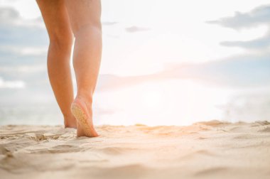 Gün batımında sahilde yürüyen bir kadın..