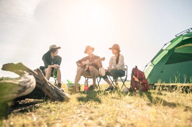Bir grup genç, kamp gezisinde davul ve gitar çalmaktan zevk alıyor..