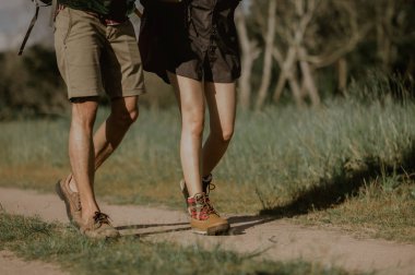 Sırt çantalı yürüyüşçüler orman yolunda yürürken dağ botları giyip ayakkabılara odaklanırlar..