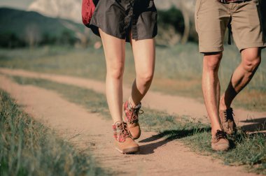 Sırt çantalı yürüyüşçüler orman yolunda yürürken dağ botları giyip ayakkabılara odaklanırlar..