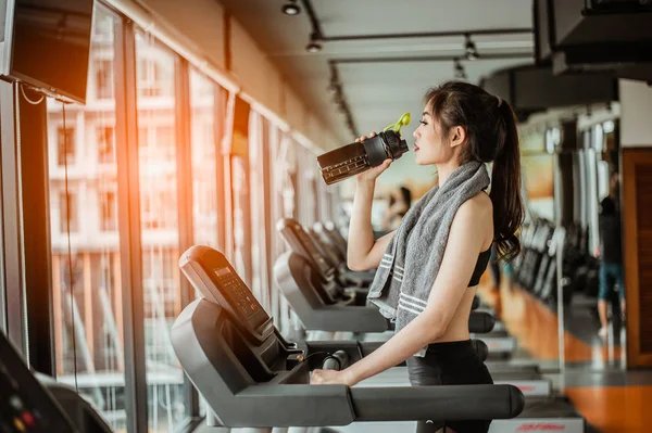 Young woman at treadmill drinking water.Young woman at treadmill drinking .protein shake.
