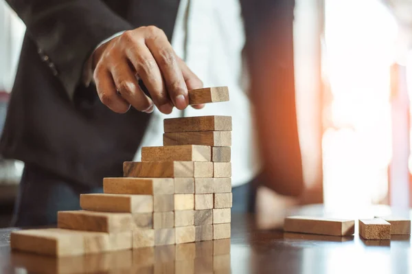 İş dünyasında plan ve strateji. Risk kavramı. İnsanın eli ahşap bir bloğu yığıp istifliyor..