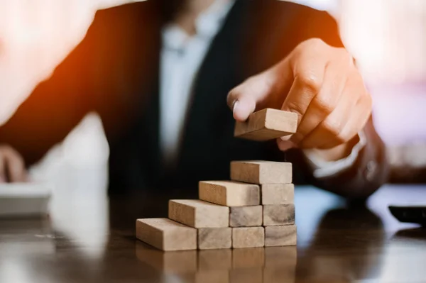 İş dünyasında plan ve strateji. Risk kavramı. İnsanın eli, tahtadan bir bloğu yığıp istifliyor. İşadamı, 
