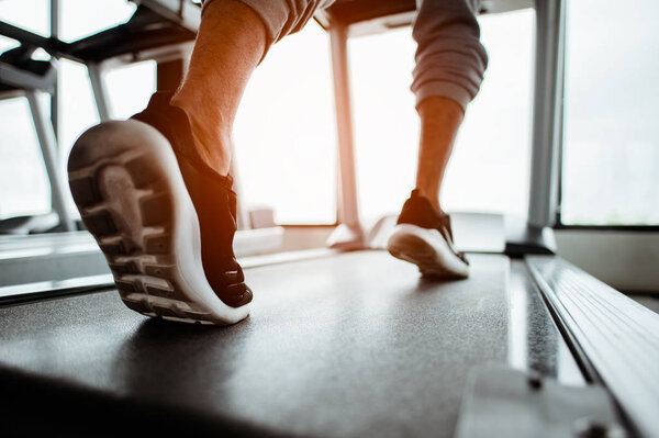 Человек бегает в тренажерном зале по треку, занимается фитнесом и ведет здоровый образ жизни 