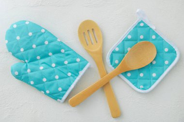 Mitten potholder için sıcak stand ve tahta kaşıklar Turkuaz renk beyaz ipeksi zemin üzerinde beyaz bezelye