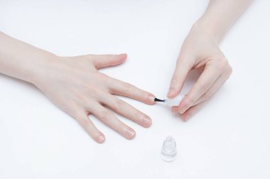 Genç kız beyaz zemin üzerine renksiz cila ile tırnaklarını boyar