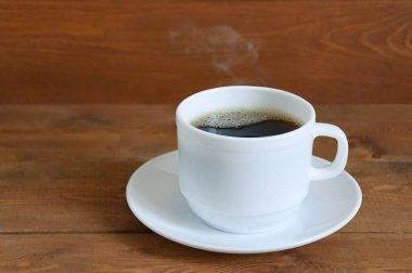 Bir daire ahşap bir arka plan üzerinde beyaz bir fincan sıcak kahve. Yakın çekim.