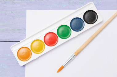 Suluboya boya fırça ve beyaz kağıt yaprağının menekşe ahşap arka plan üzerinde. Kapat-u