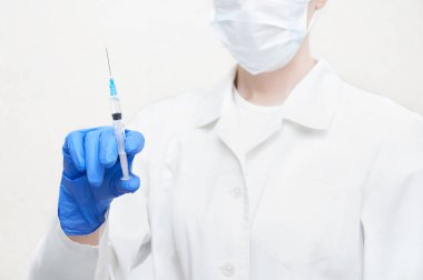 Beyaz önlük ve steril eldiven bir doktor ilaç şırıngayla elinde tutar. Yakın çekim.