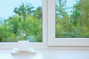 Beyaz Kupası ve fincan tabağı yaz penceresinde üzerinde.