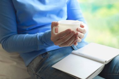 Bir kız çay içme ve bir kitap okuma. Yakın çekim.