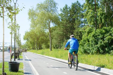 Novosibirsk 07-31-2018. Bir adam Rıhtımlar üzerinde parkta bisiklete biniyor.