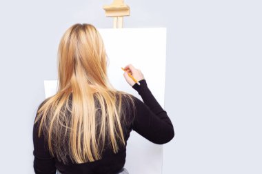 Kız tuval üzerinde bir kalemle çizer..