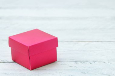 Beyaz ahşap zemin üzerinde kırmızı küçük kutu. Yakın çekim.