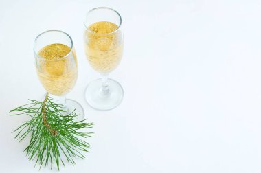 İki kadeh şampanya ve ladin beyaz bir tabloda bir dalı ile.