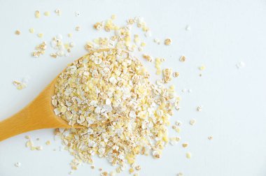 Tahta kaşık ve saçılma yulaf ezmesi. Beyaz arka plan.