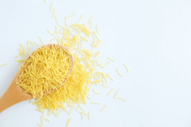 Tahta kaşık ve saçılma küçük erişte. Beyaz arka plan.