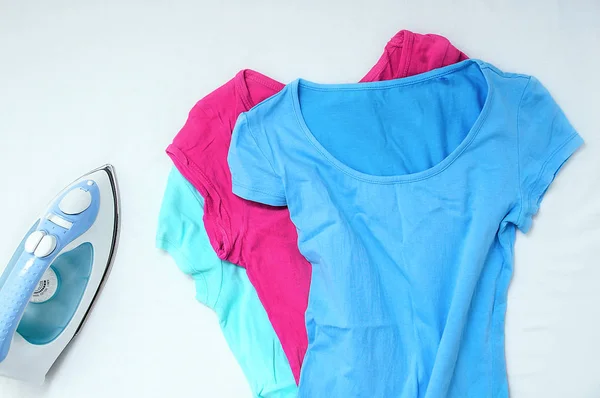 Wrinkled clothes and iron on a white background. View from above.