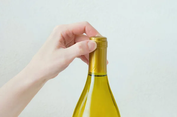 Hand caucasian girl opens a bottle of wine. Close-up. White background.